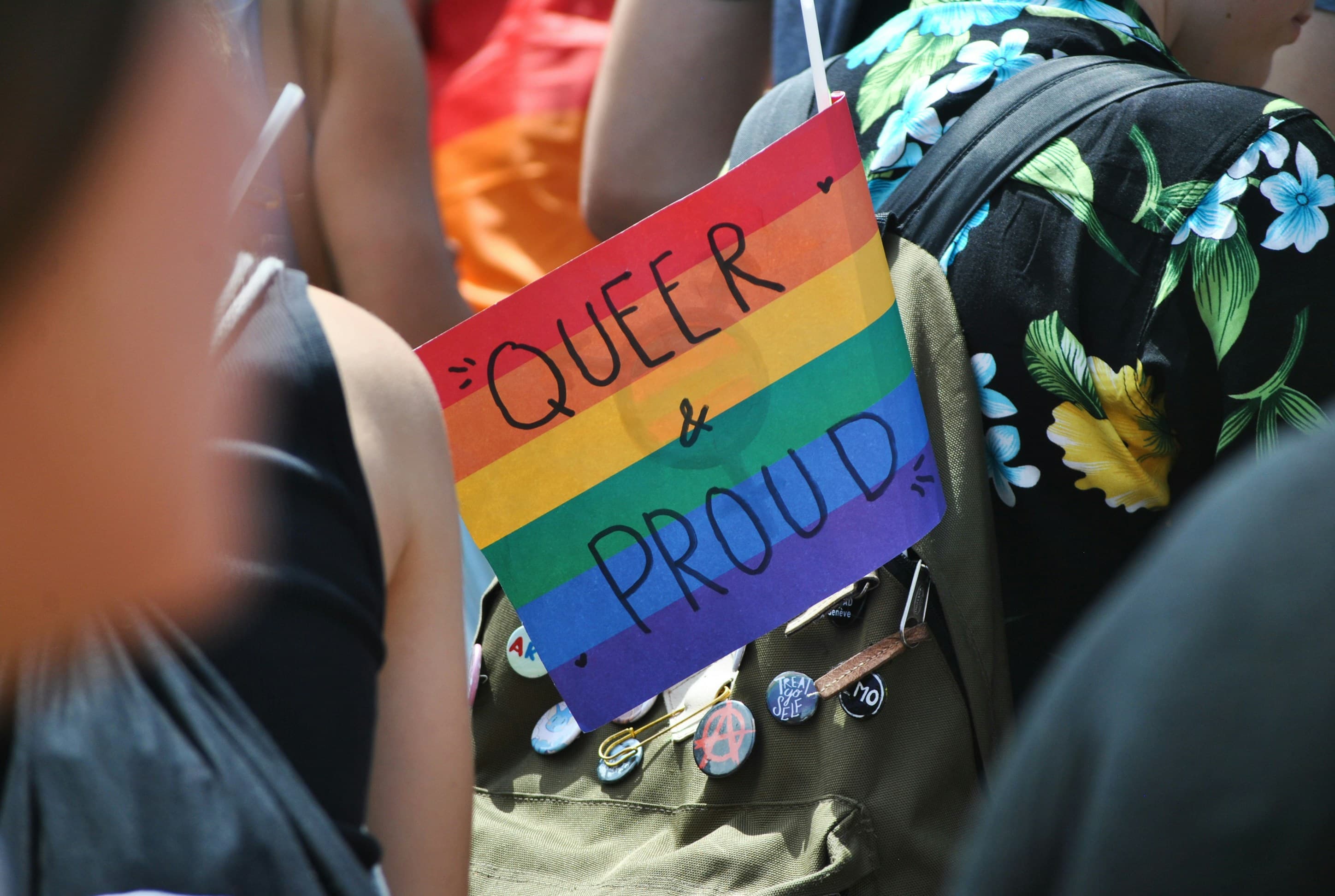 LGBTQ+ rainbow pride flag in a backpack with the words, "Queer & Proud" on it.