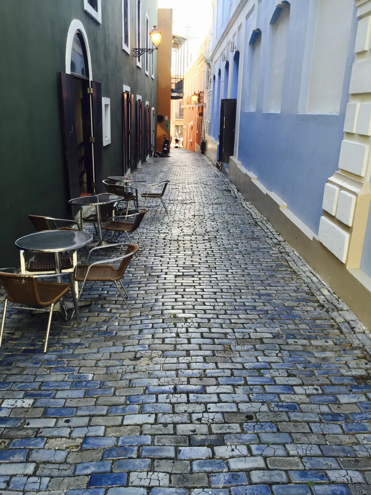 A narrow street of blue cobblestones lined with colorful colonial houses in Old San Juan, Puerto Rico
