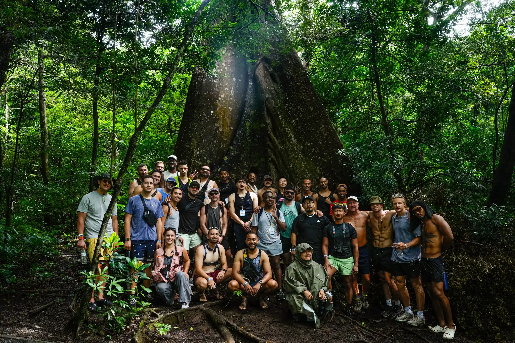 A Visiting Wrld retreat group posing at the base of a giant ceiba tree in the Costa Rican rainforest
