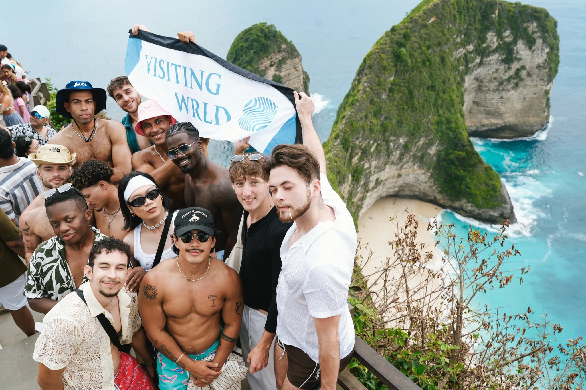 The Visiting Wrld group with the flag above Kelingking Beach on Nusa Penida, Bali