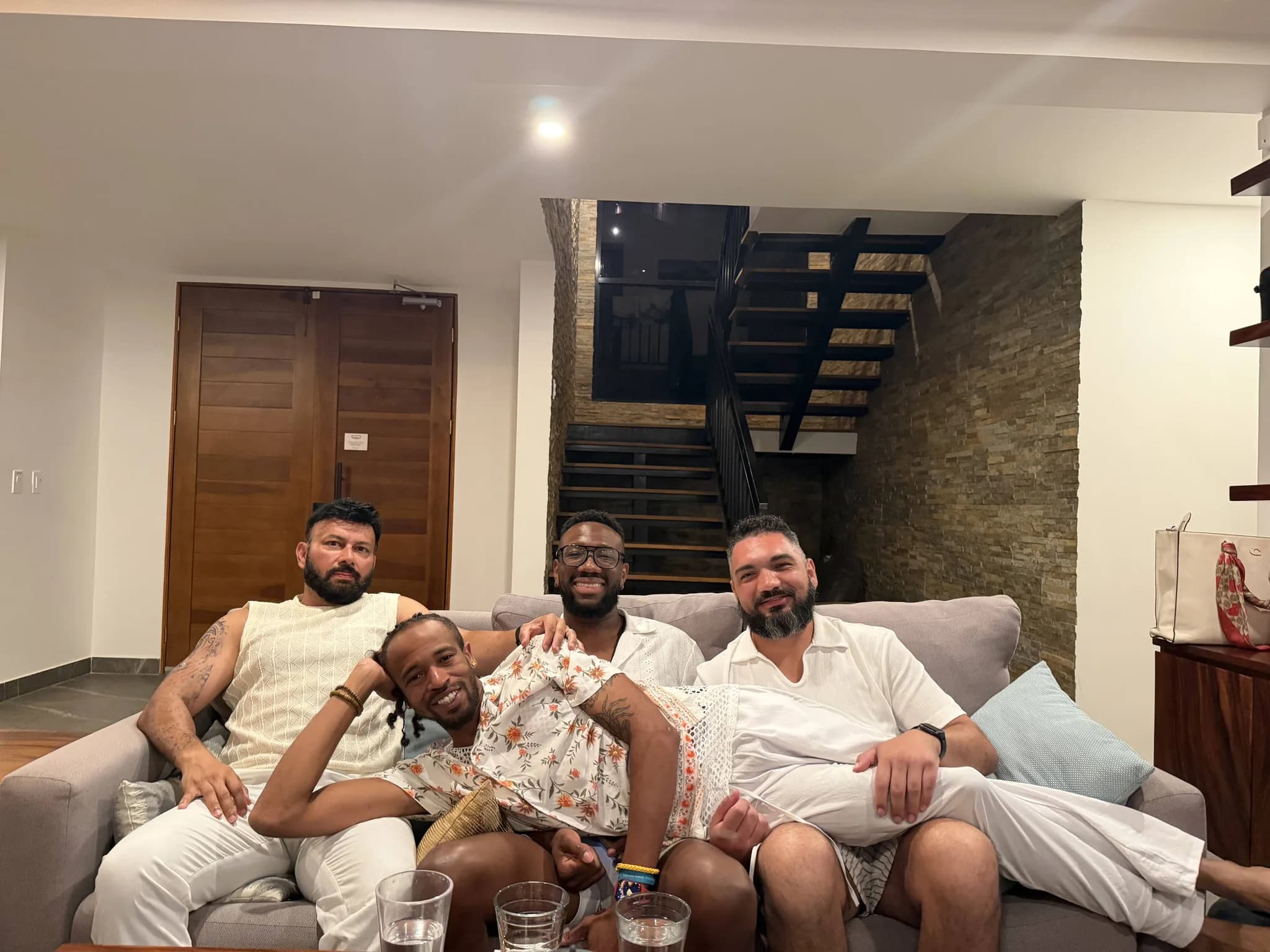 Four gay men winding down together on a couch at the retreat villa on white party night