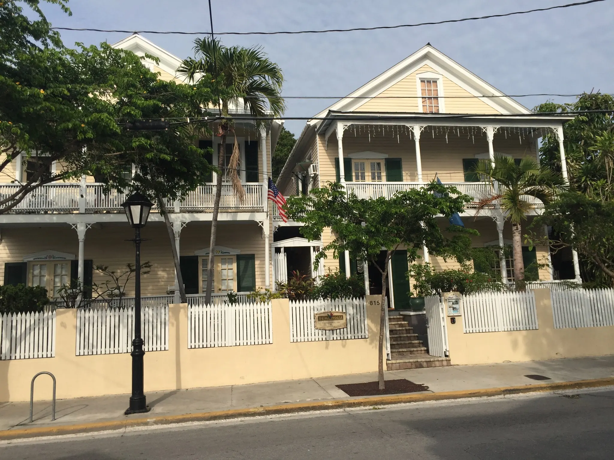 A two-story white porch house with a picket fence on Duval Street in Key West