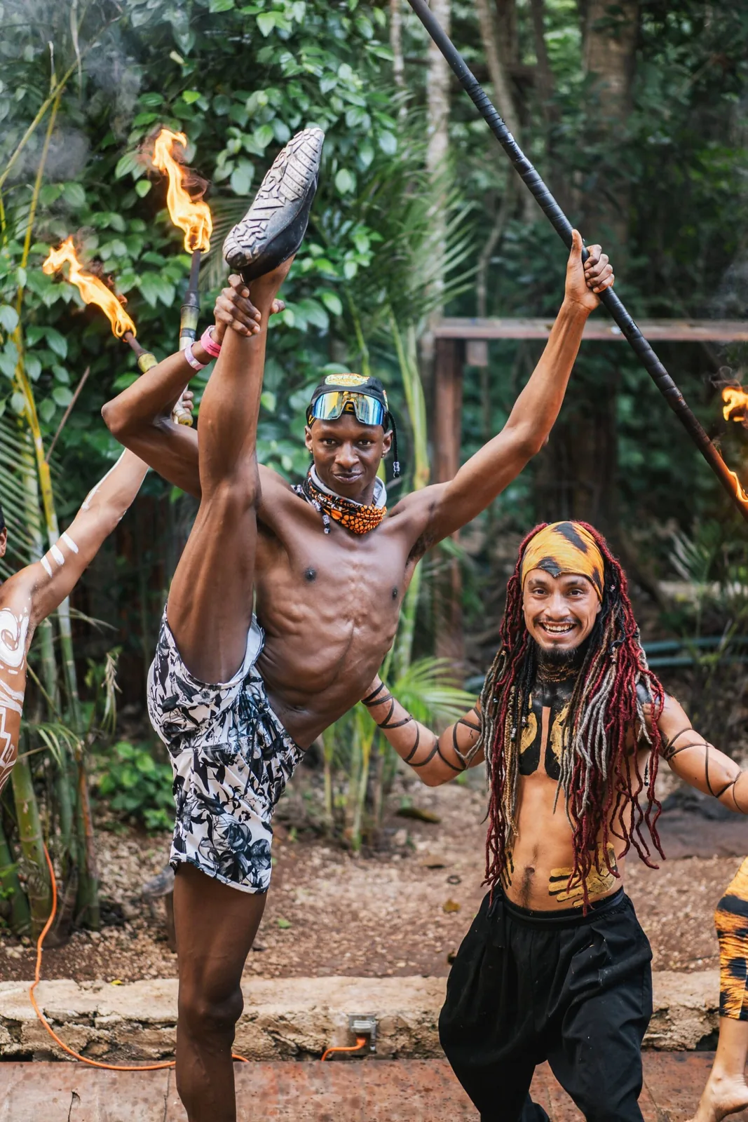 A talented performer executing an impressive leg stretch while holding a flaming staff, exuding confidence and skill