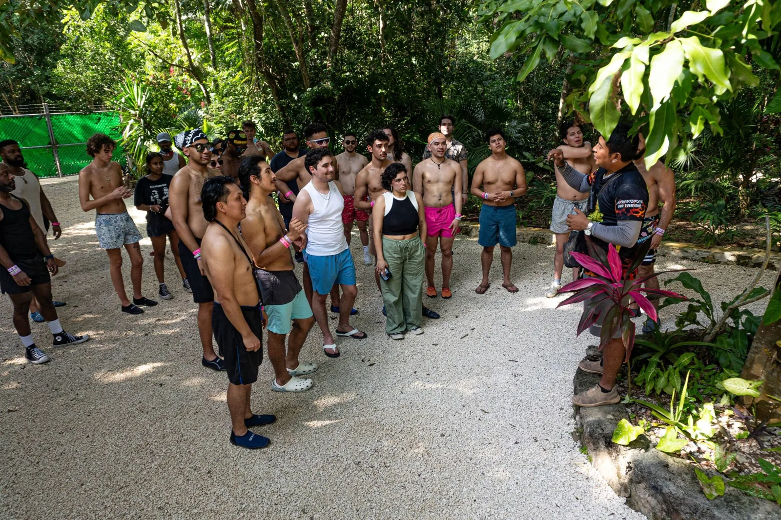 A group of attendees listening attentively to a guide in a lush outdoor setting