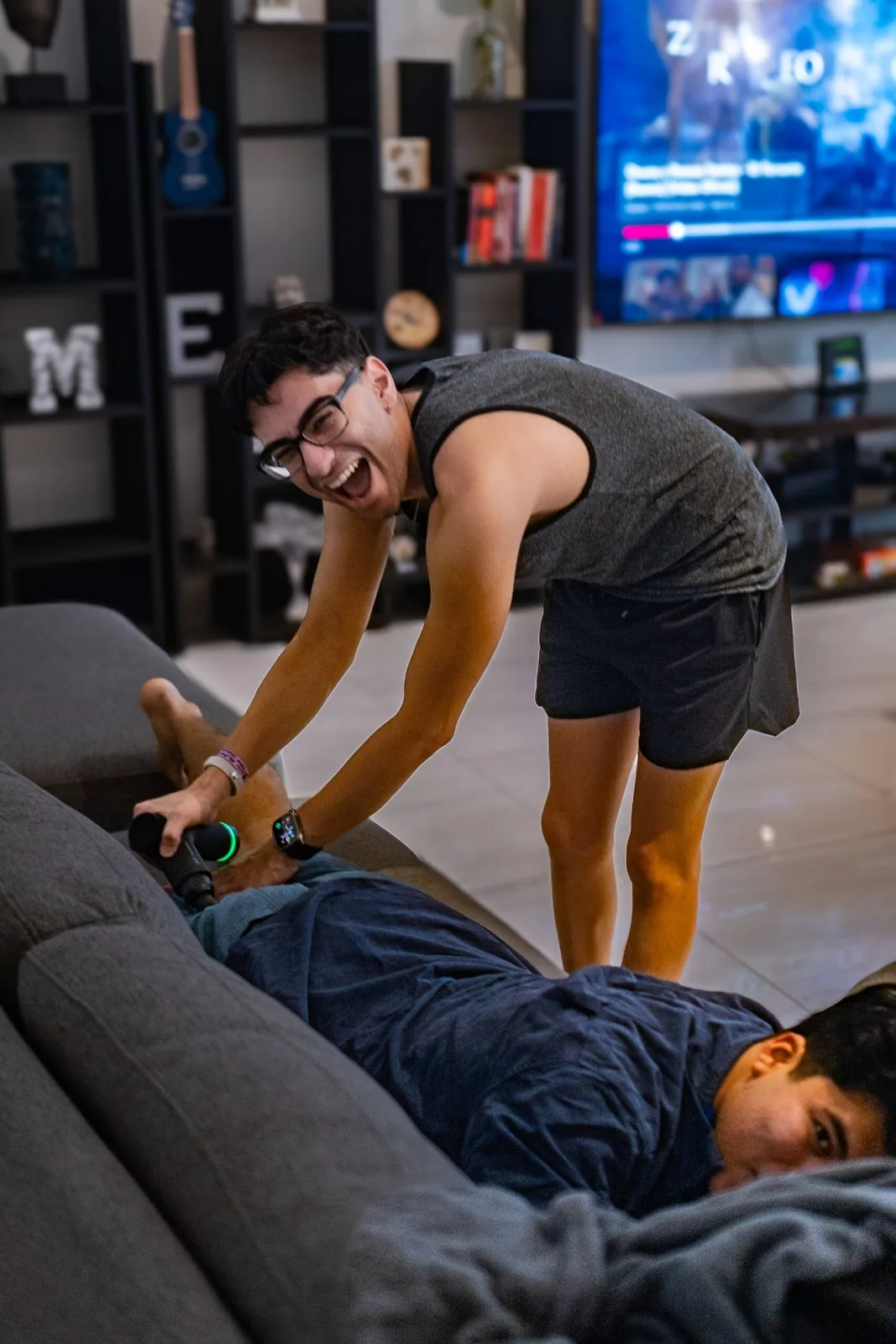 A retreat participant laughing while using a massage gun on another participant, creating a fun and lighthearted moment