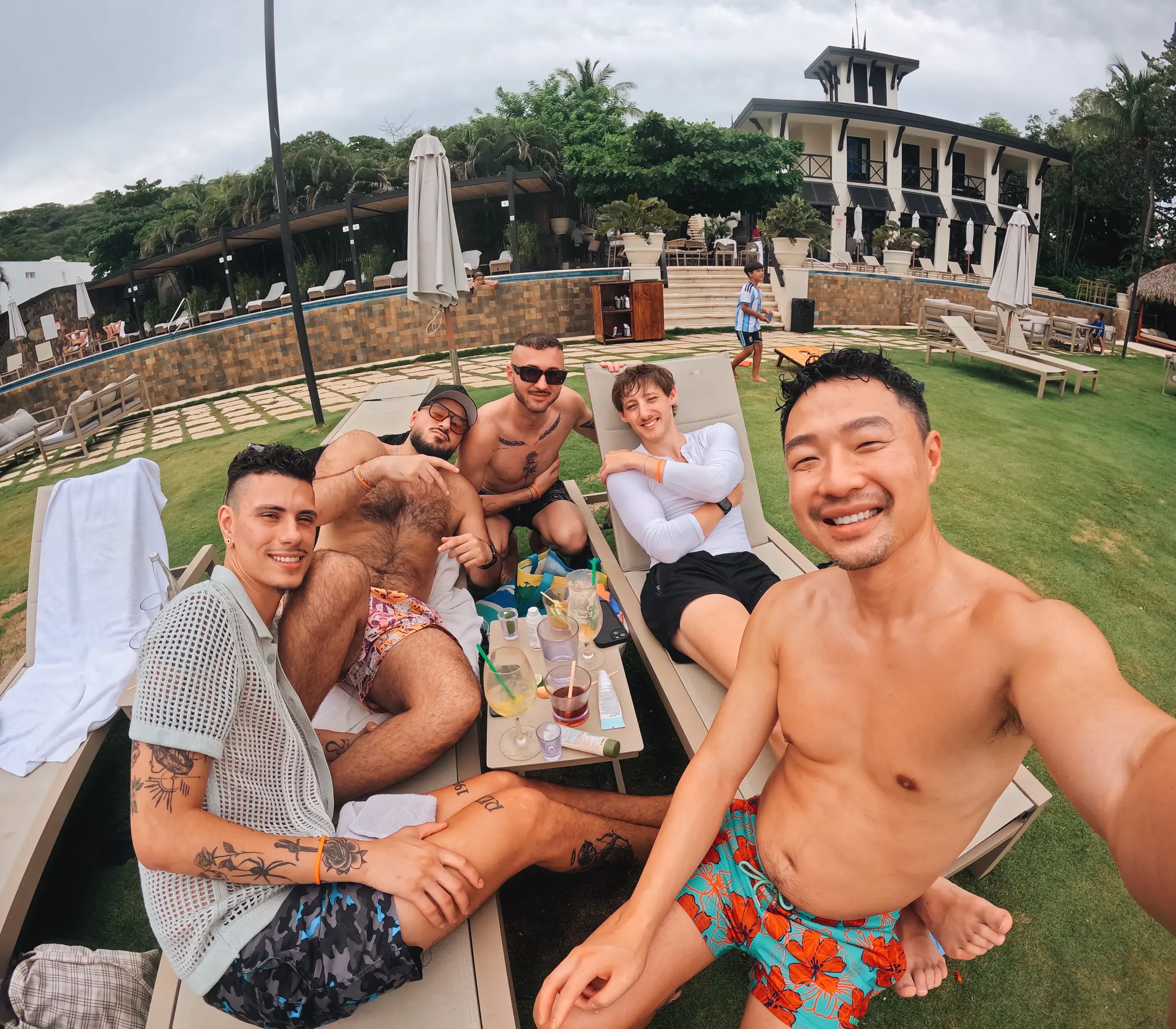 Five Visiting Wrld retreaters on pool loungers with drinks, taking a group selfie on a retreat abroad