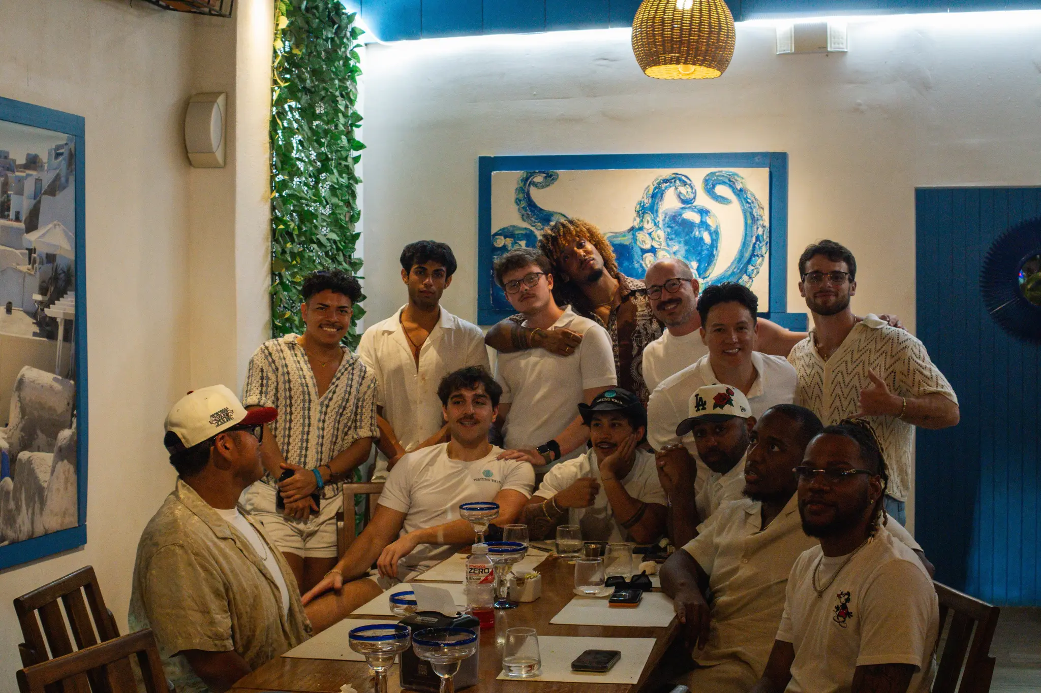 A Visiting Wrld retreat group around a long table at a dinner out, most of them in white