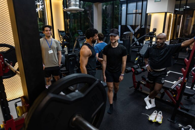 Group of retreat participants engaging in weightlifting and conversation in the gym