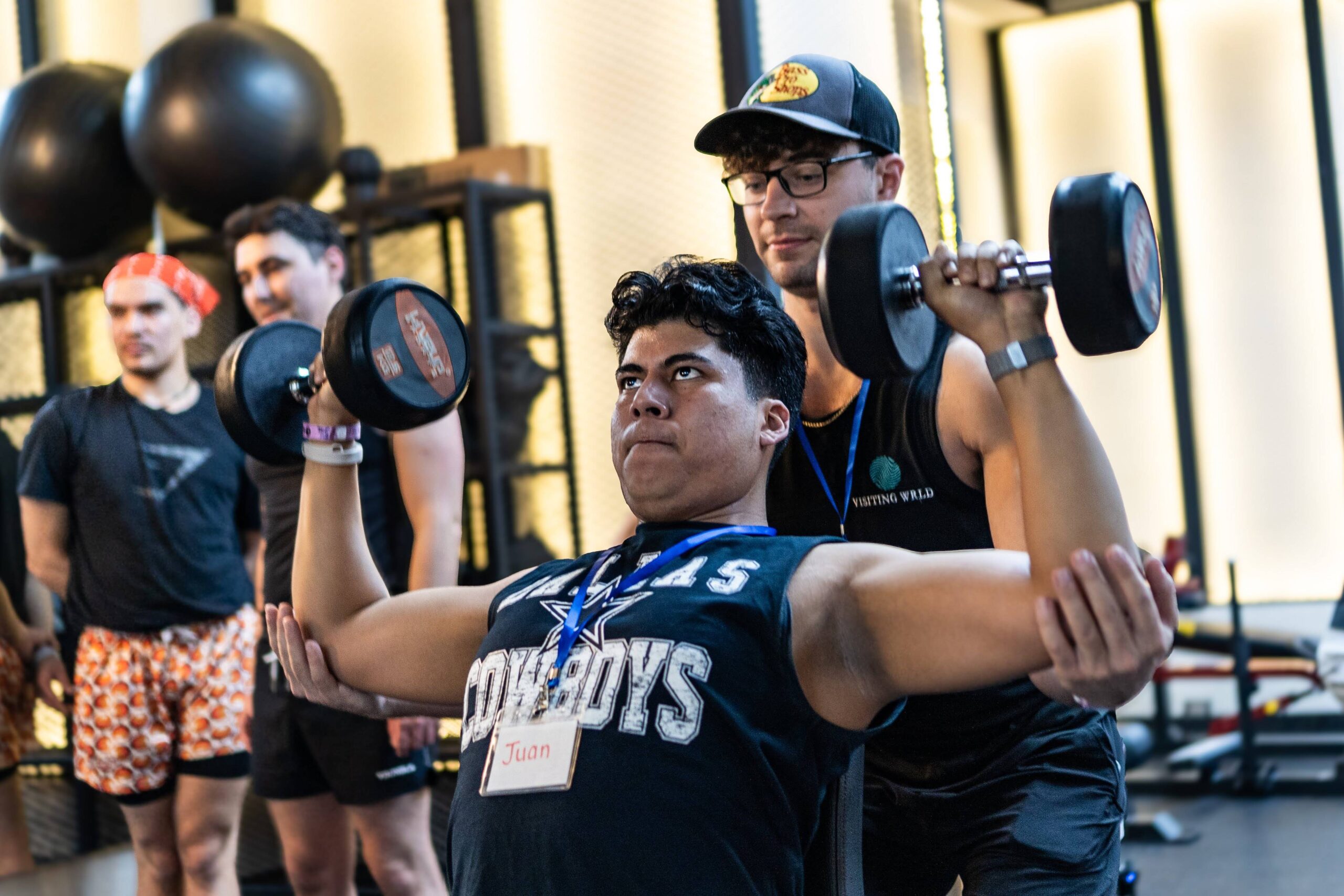Retreat participant lifting dumbbells with a coach spotting during a Visiting Wrld LGBTQ+ fitness retreat