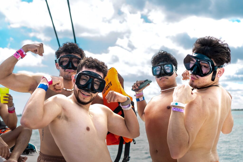 LGBTQ+ men flexing with goggles on in front of an ocean