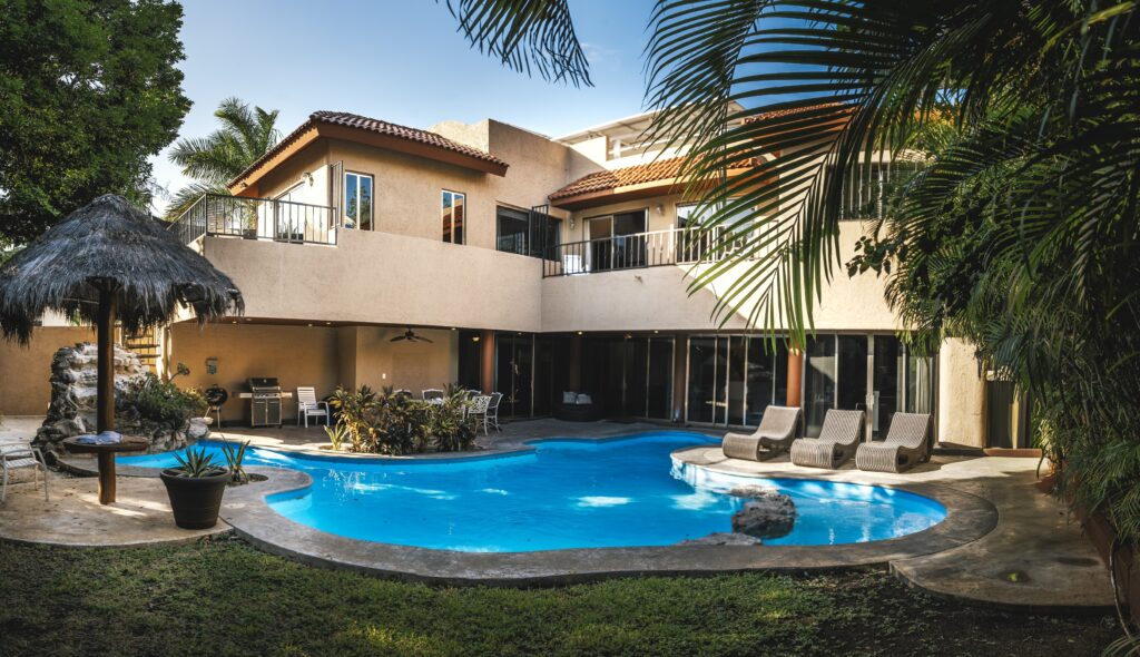 A house-styled villa with a pool and seating throughout the area